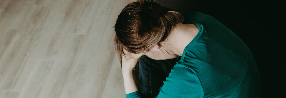 woman in green shirt with head in hands