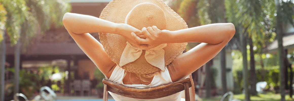 woman in sunhat with hands behind her head - back view