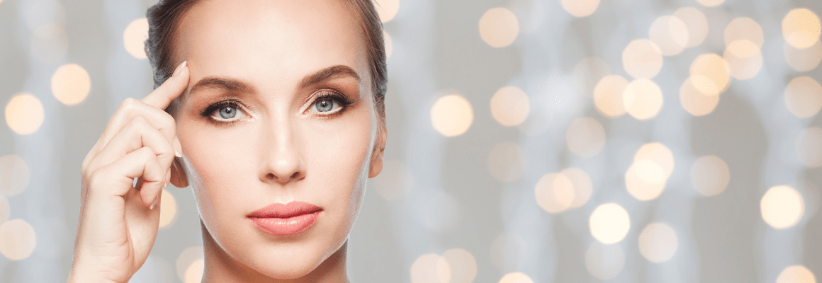 woman pointing to forehead while lights gleam in background