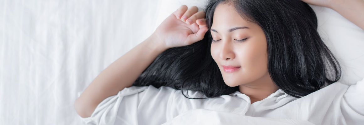 Woman lying on a bed sleeping with a slight smile.