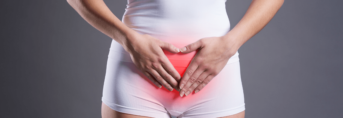 woman in white holding heart hands over groin area