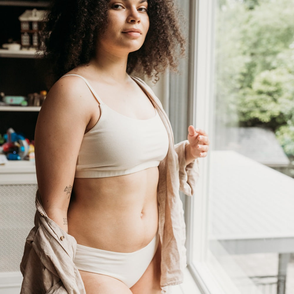 Woman by a window in a soft natural organic cotton bikini set, comfortable underwear for dermatitis-prone skin