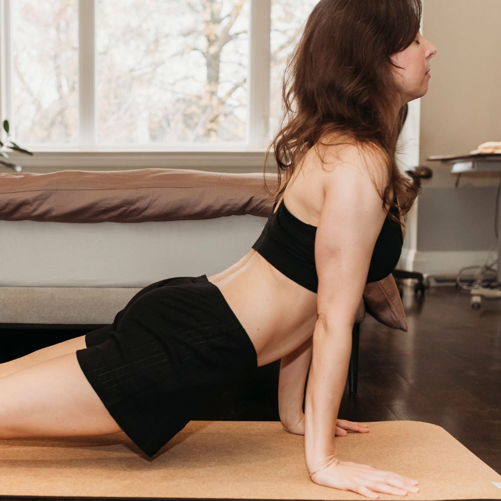 Woman stretching on a yoga mat in relaxed-fit black organic cotton boxers that let skin breathe