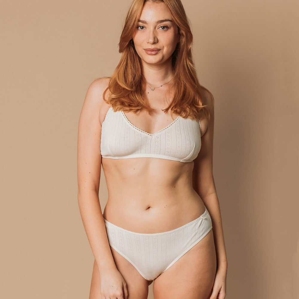 Woman wearing a natural pointelle French cut bikini and bralette in eczema-friendly organic cotton
