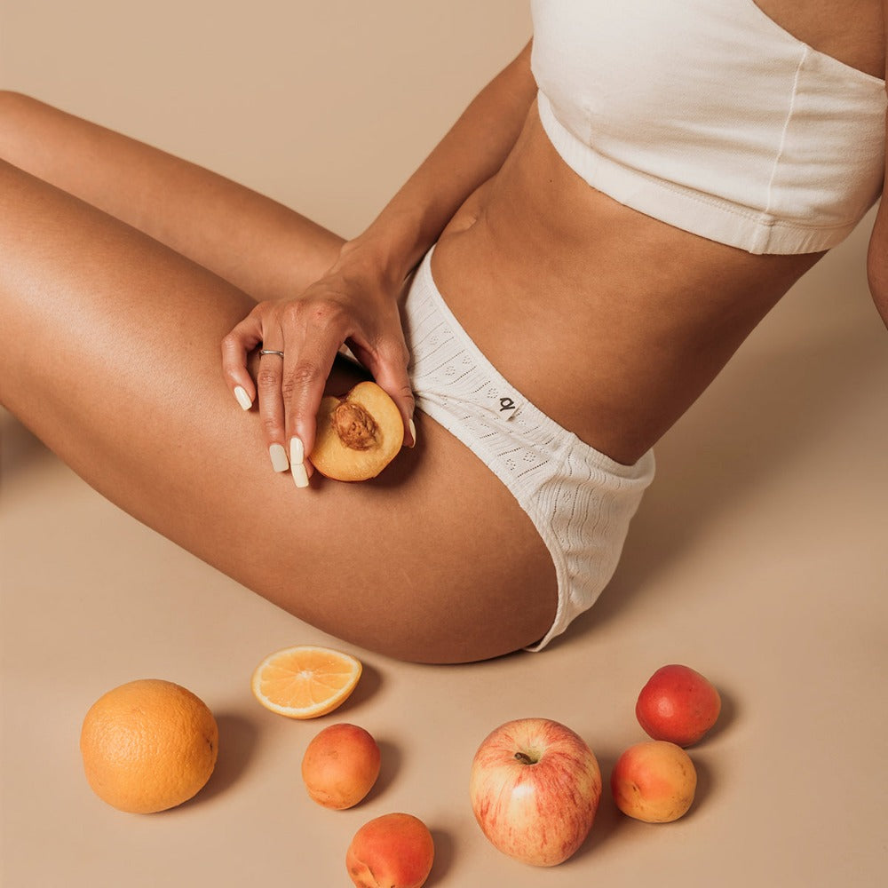 Woman seated with fruit wearing a natural organic cotton French cut bikini