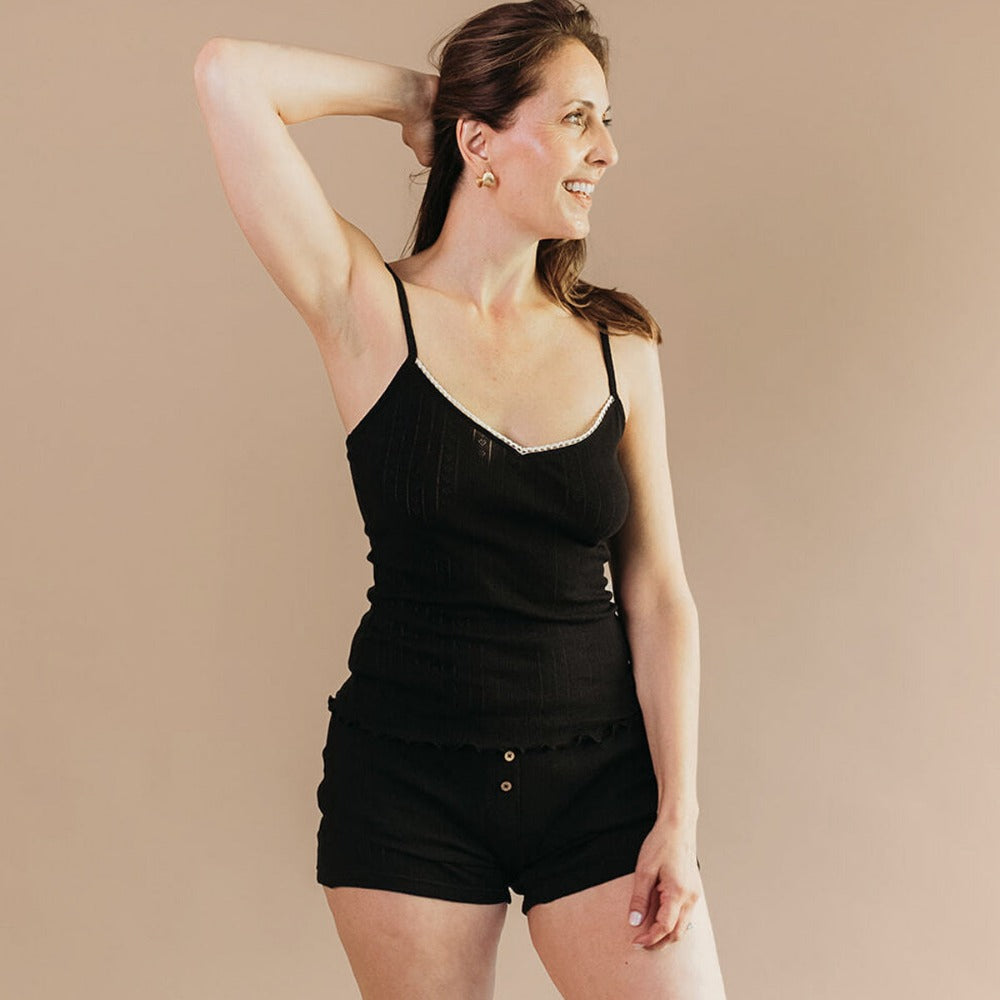 Woman in a black pointelle tank top and boxers, an eczema-friendly organic cotton sleep set