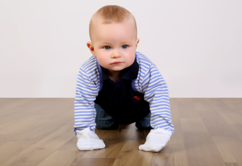 Baby boy crawling on the floor while wearing his white and white striped cotton scratchsleeves with scratch mittens in silk.