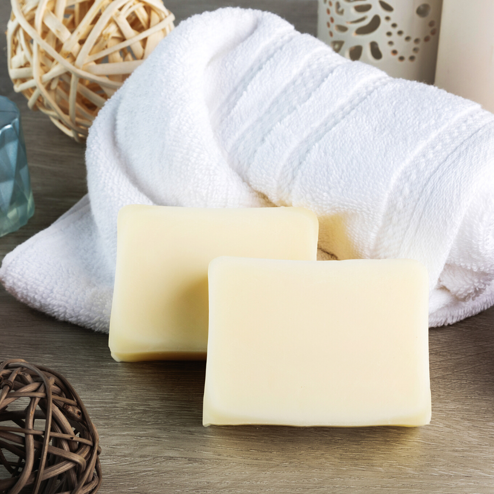 two bars of tallow soap resting on a rolled up white towel.