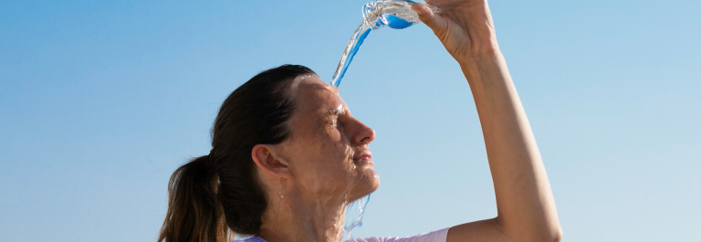 woman pouring a water bottle on her face 