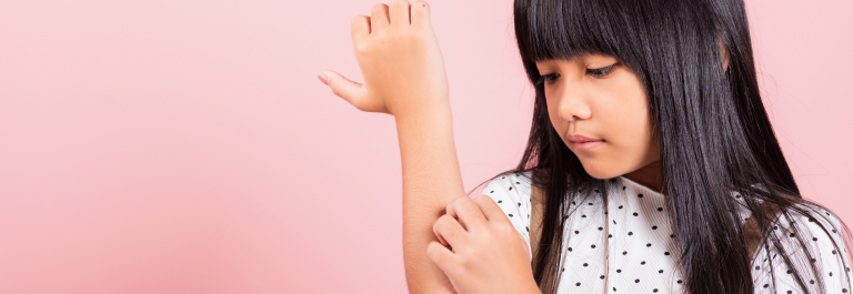 little girl scratching arm against pink background
