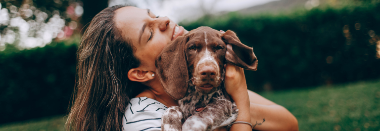 woman cuddling a small brown dog 