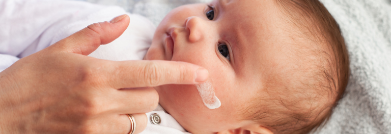 person putting natural cream on baby's cheek to soothe eczema