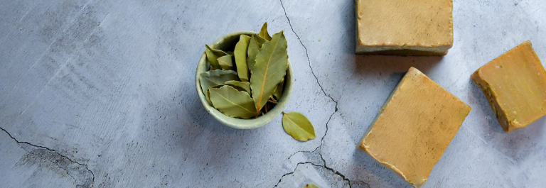 bowl of leaves and lye soap against grey background