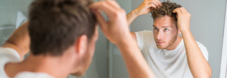 man checking hair in the mirror