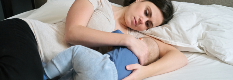 mother breastfeeding her baby lying on bed 