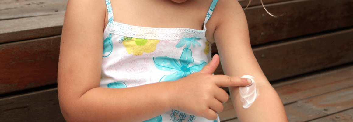little girl putting cream on arm