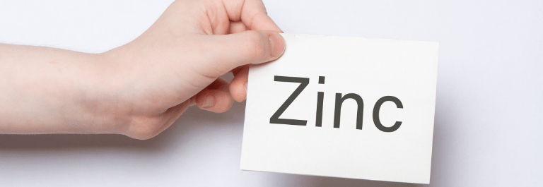person holding a piece of paper that says 'zinc'
