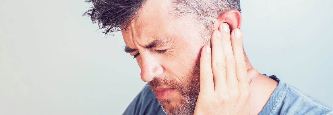 man touching ear in pain