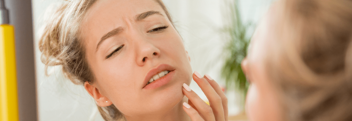 blonde woman looking at pimple on chin
