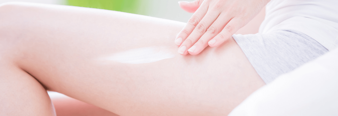Image of a woman rubbing cream onto her upper leg.