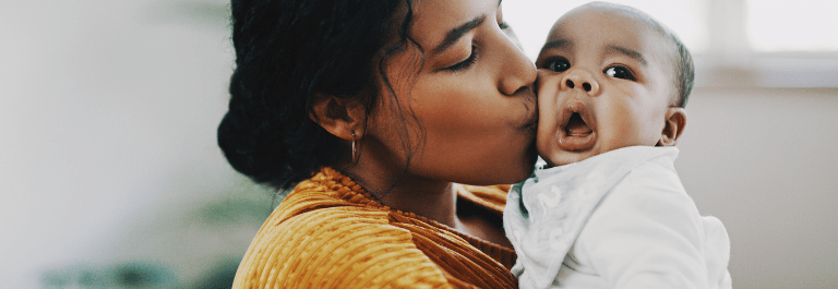 mother kissing baby on cheek