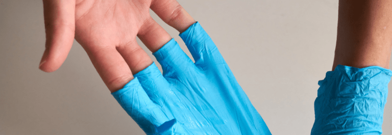 person pulling off blue latex gloves