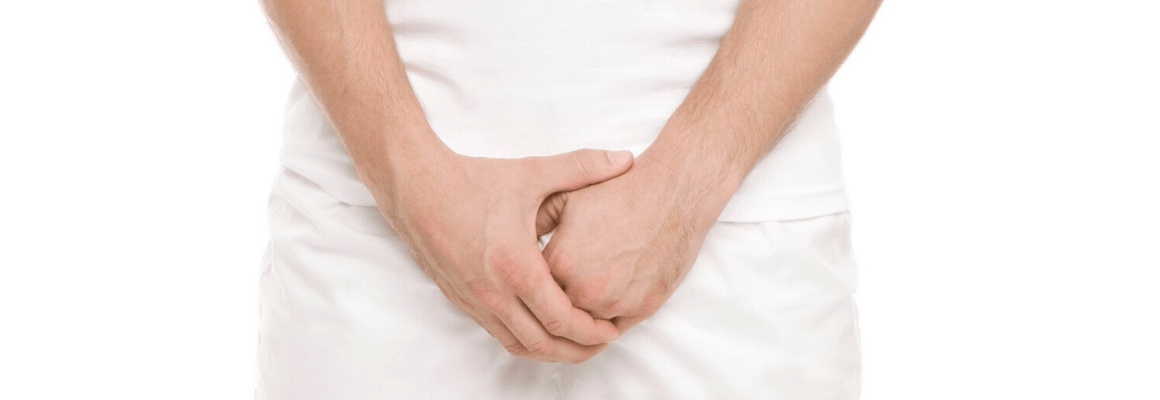 man wearing all white holding hands over crotch area