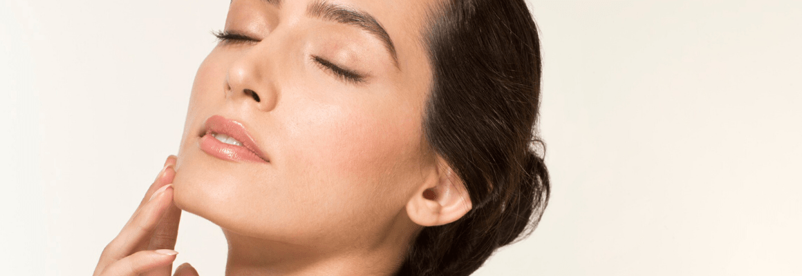 woman in bun with eyes closed touching her face