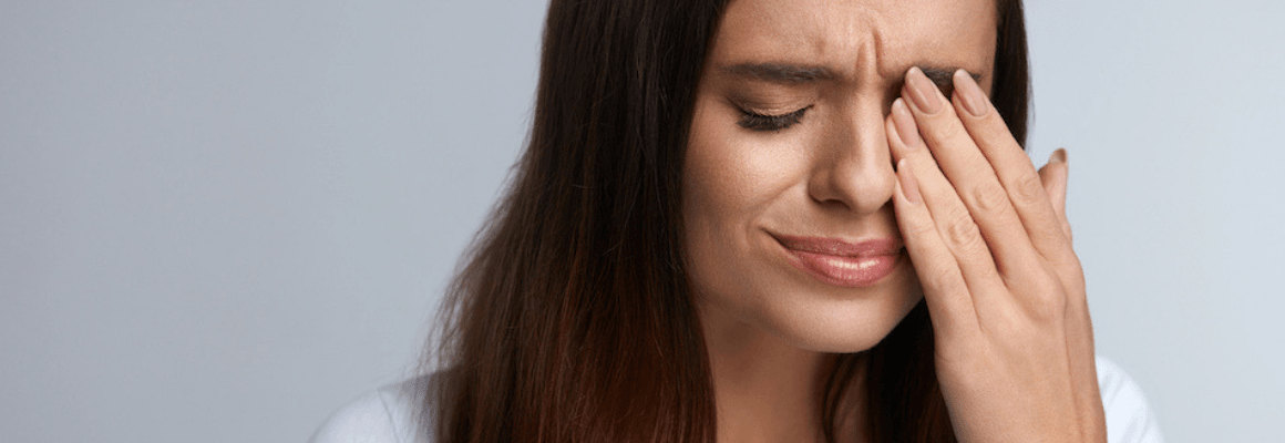 woman frowning and holding her eye
