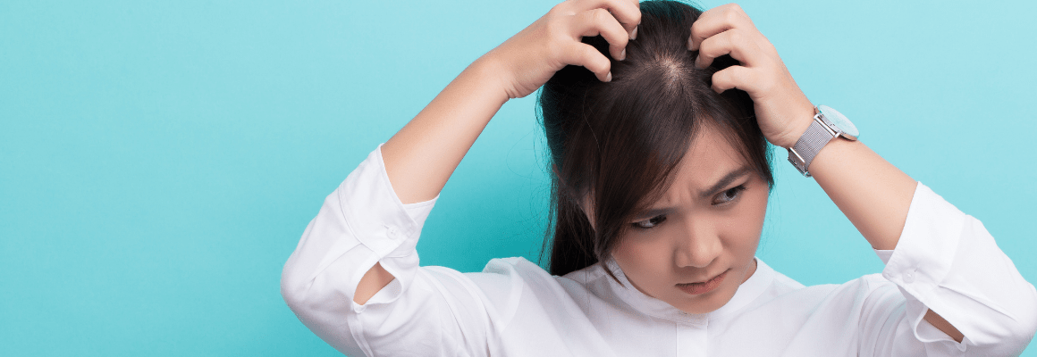 woman in white shirt scratching scalp against blue background