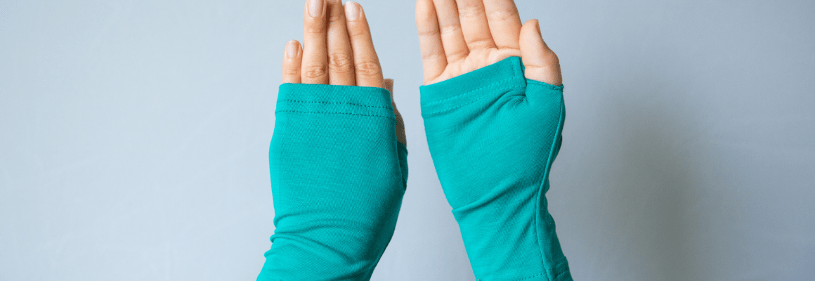 person wearing green fingerless gloves against grey wall