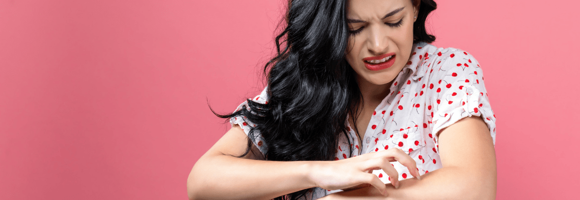 woman scratching arm with pink background