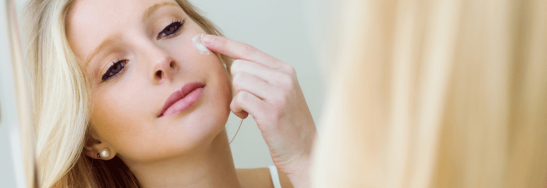 blond-haired woman putting cream on face