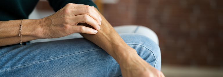 man in jeans scratching arm