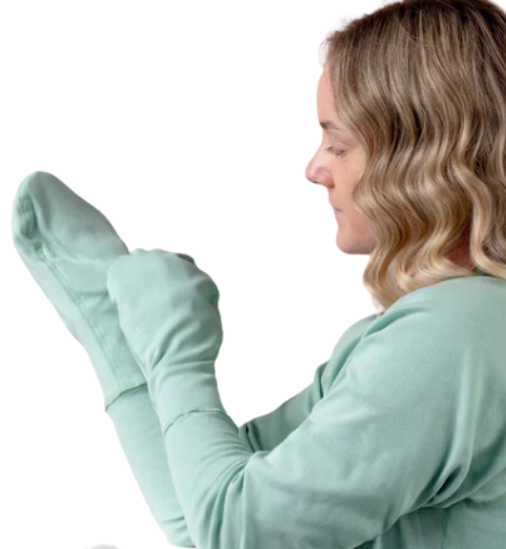 Woman standing while wearing a mint green cotton top with closed eczema mittens for adults