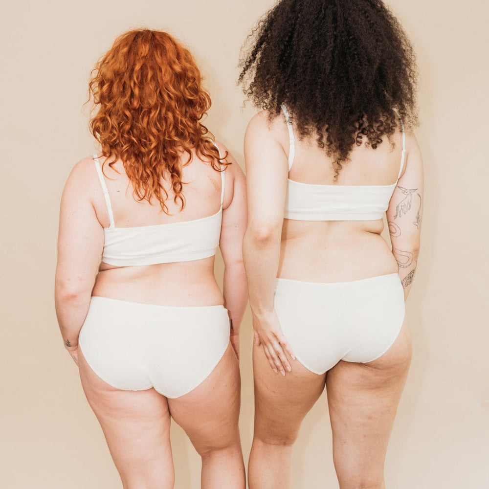 Back view of two women in breathable, tagless organic cotton bikini underwear in natural color
