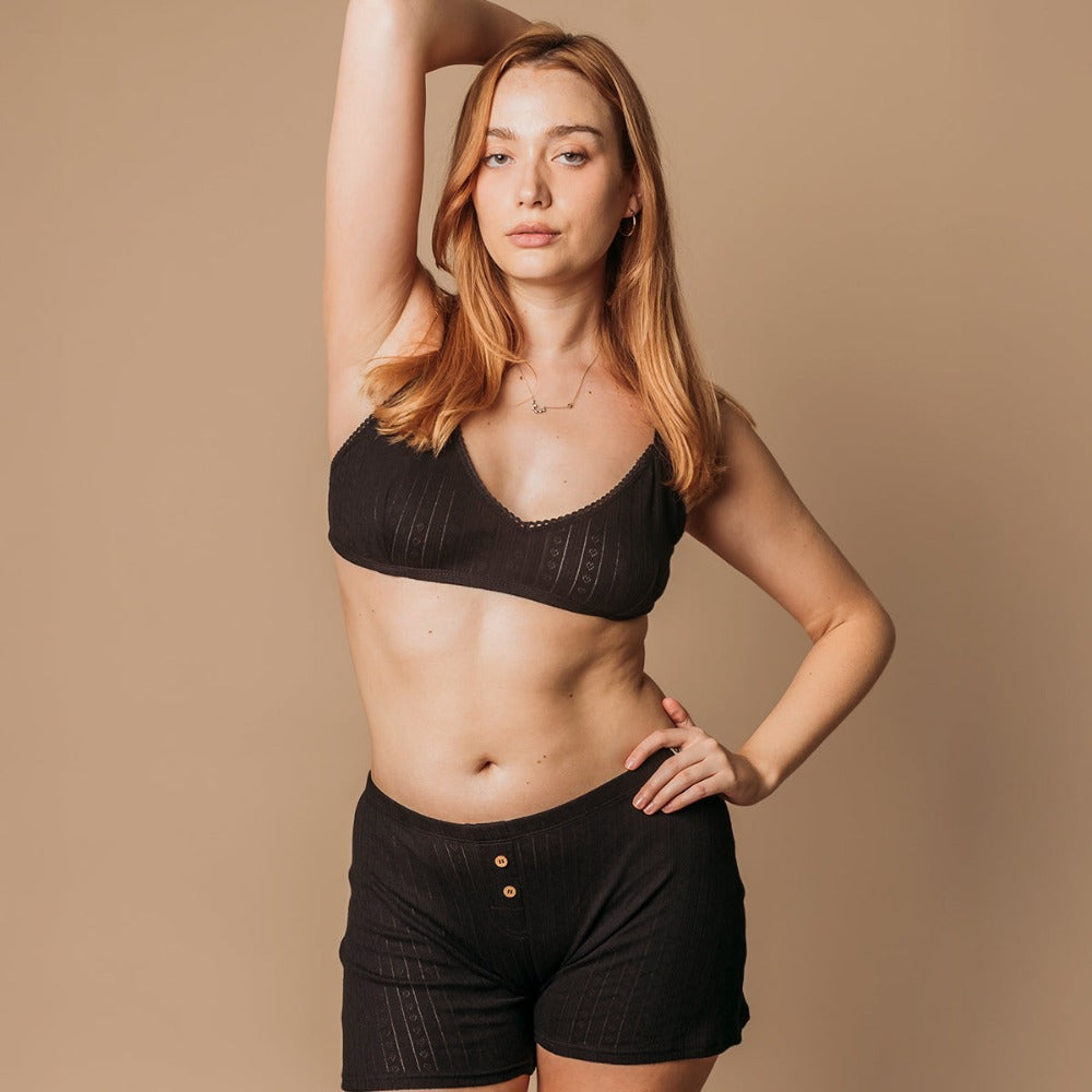 Woman in black pointelle boxers and bralette, eczema-safe organic cotton sleep set