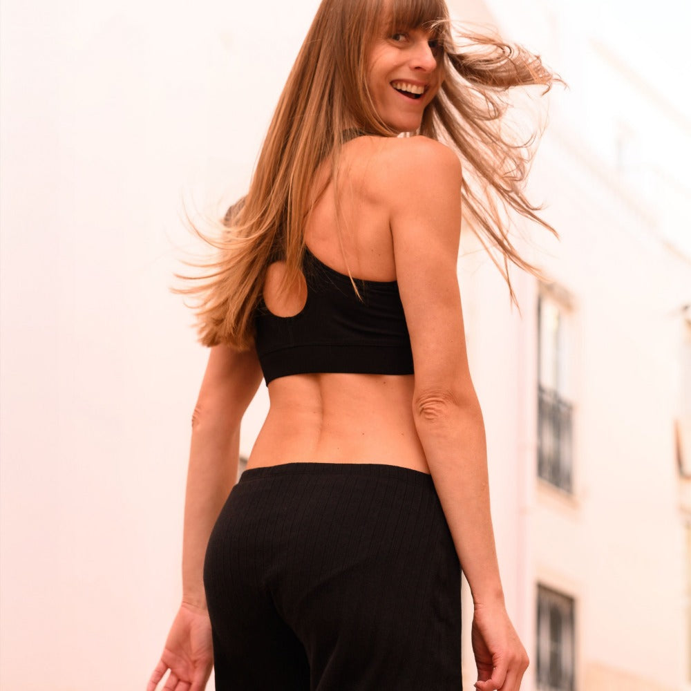 Woman smiling over her shoulder in black pointelle boxers, gentle cotton for sensitive skin