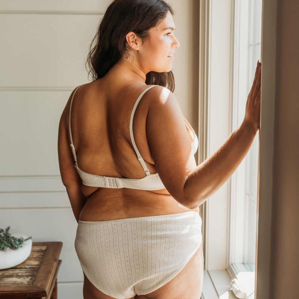 Curvy woman by a window in a natural French cut bikini, breathable organic cotton