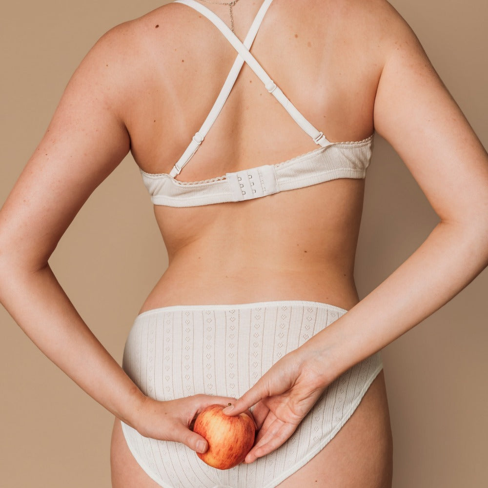 Back view of a woman in a natural bralette and French cut bikini made from gentle organic cotton