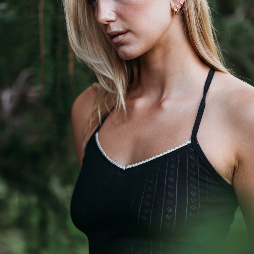 Close-up of the black pointelle tank top's cotton lace trim and open-knit organic cotton