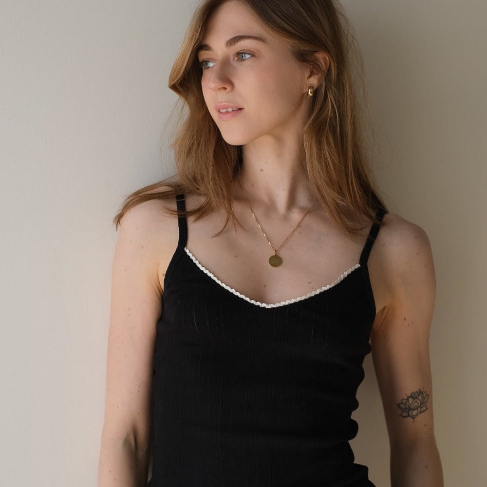 Woman in a black tank top with contrast lace neckline, soft organic cotton for sensitive skin