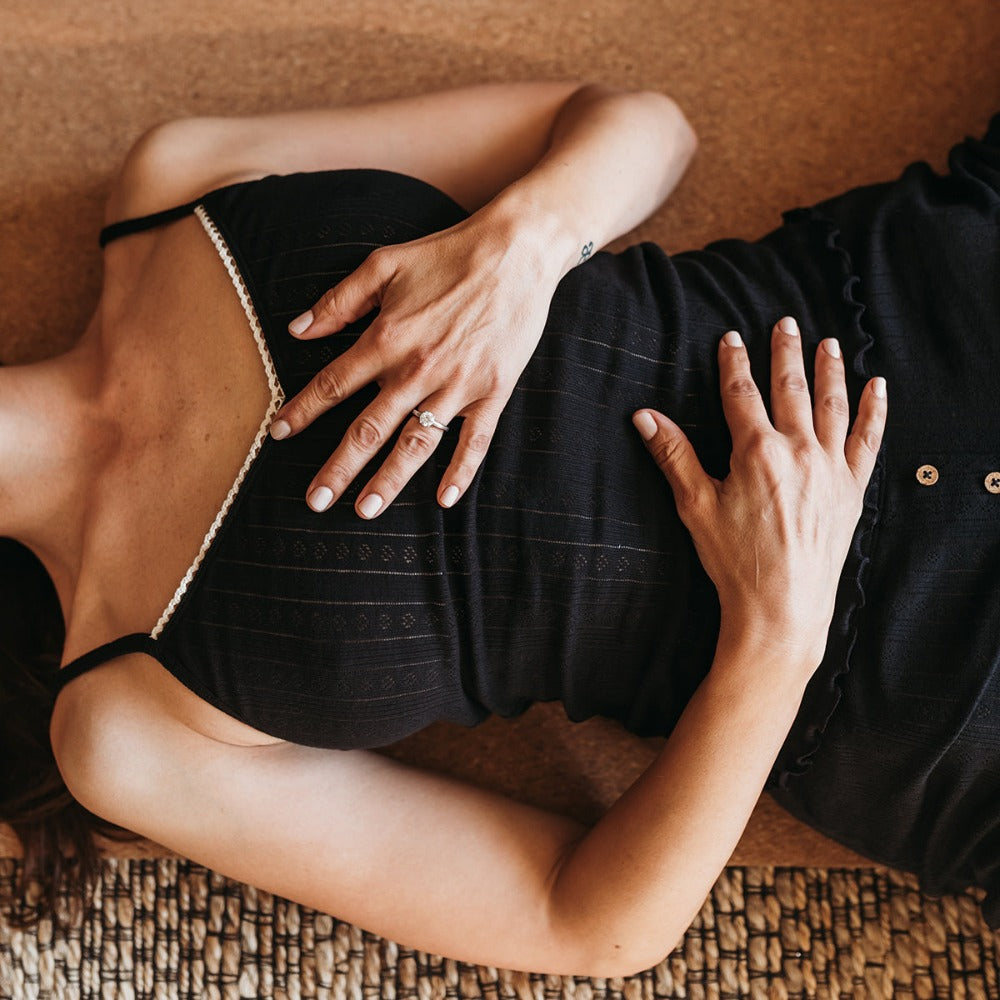 Woman lying down in a black pointelle tank top, soft organic cotton loungewear