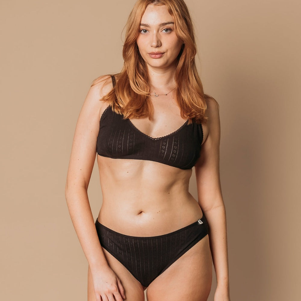 Woman in a black mid-waist pointelle thong and bralette made of organic cotton