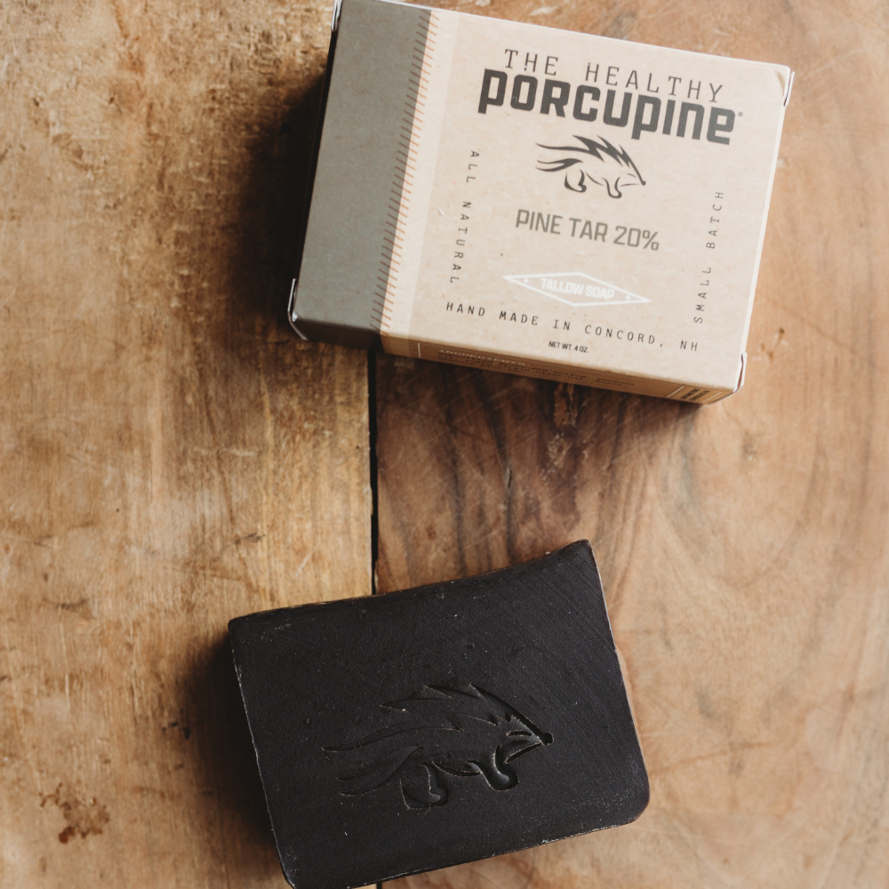 Black soap bar with 'The Healthy Porcupine' packaging on a wooden surface