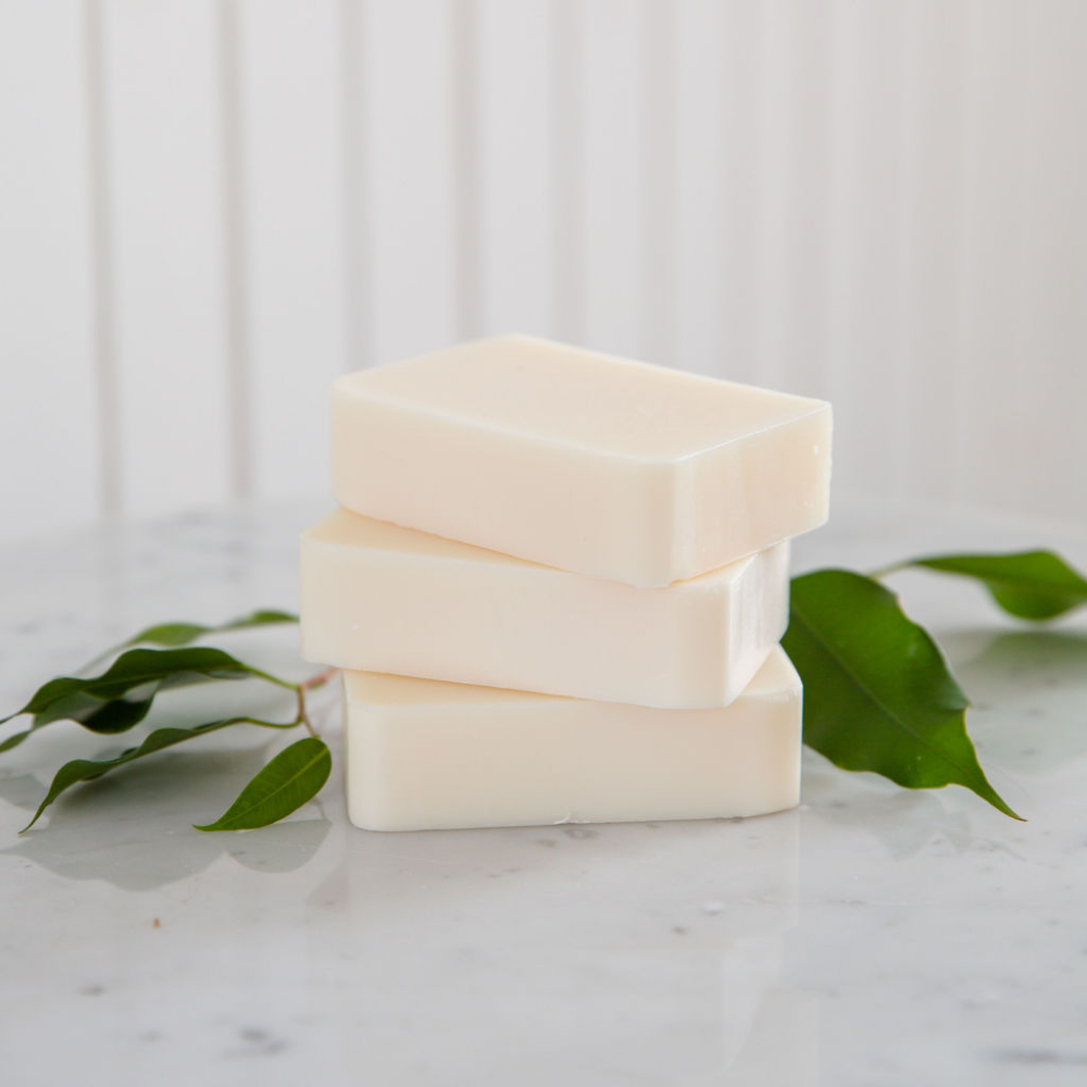three stacked soap bars with leaves around them on a marble countertop