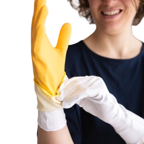 Woman putting a yellow rubber glove over her cotton gloves.