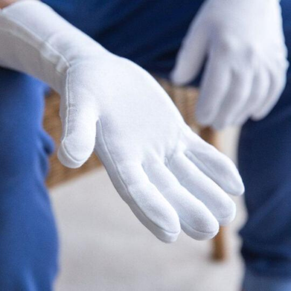 Close up of the palm of a pair of white cotton gloves.