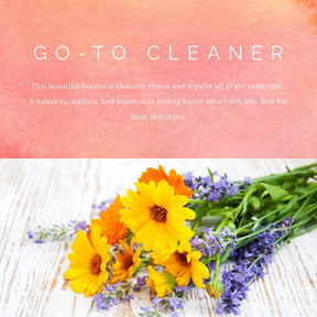 Calendula and lavender flowers laying on wood with caption stating "go to cleaner. this beautiful botanical cleanser cleans and repairs all at the same time. it balances, soothes, and leaves skin feeling better after every use. best for most skin types.
