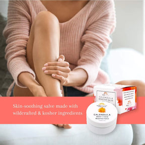Woman applying the organic calendula salve to her legs. In the foreground the salve jar and box are shown.